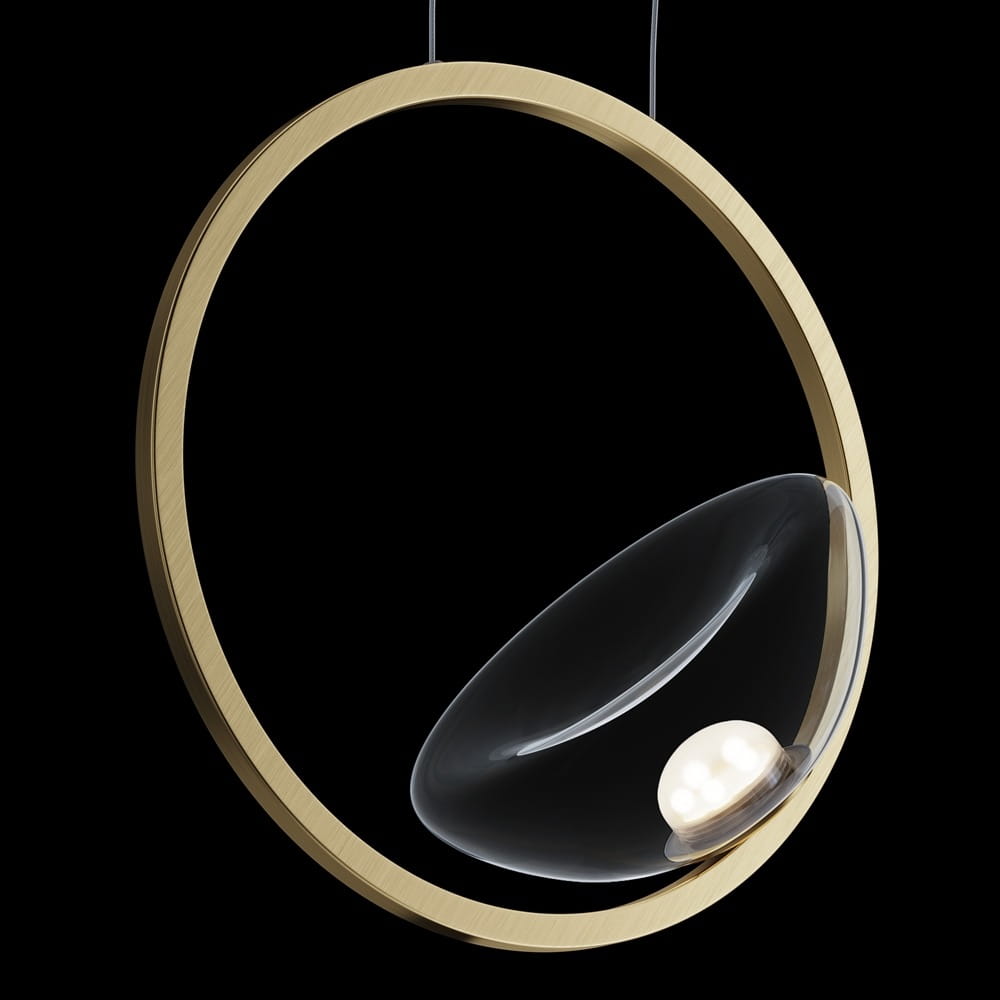 Lampa wisząca LED Lunare z mosiężnym pierścieniem i przezroczystym kloszem, w kształcie owalnej miski. Widoczny źródło światła w centralnej części. Zawieszona na cienkich linkach, na czarnym tle.