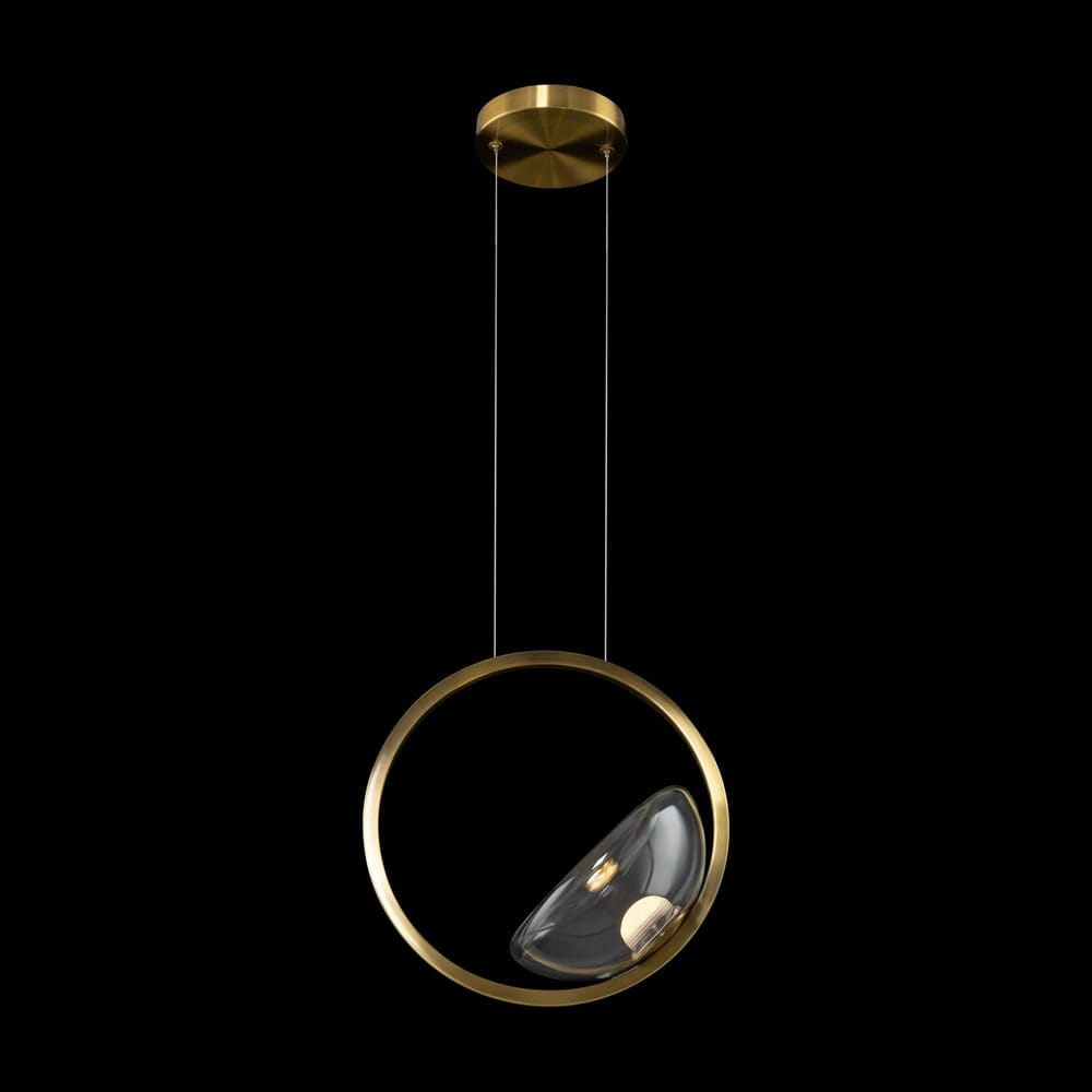 Lampa wisząca Lunare LED z mosiężnym stelażem, z okrągłym elementem zawierającym szklany klosz w formie półkuli. Zawieszona na cienkich linkach, z widocznym włącznikiem w dolnej części. Tło czarne, podkreślające elegancję designu.