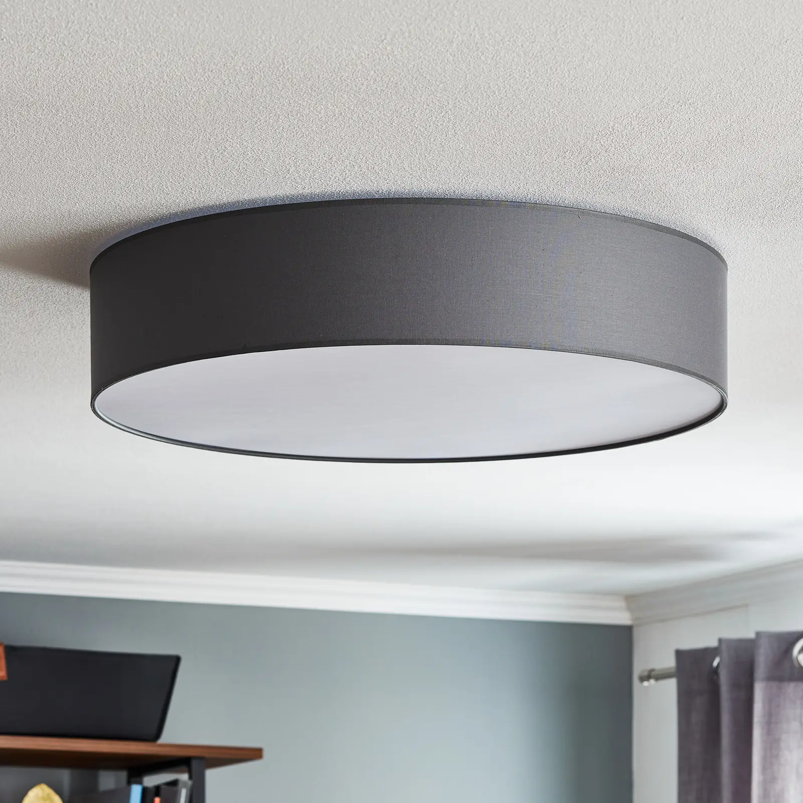 Plafon Rondo D60 w kolorze szarym, o okrągłym kształcie i średnicy 60 cm. Zamontowany na suficie, z białym kloszem, w minimalistycznym stylu, idealny do nowoczesnych wnętrz. Tło w jasnym kolorze, z elementami drewnianymi w otoczeniu.