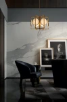 Lampa wisząca Marmo 6-punktowa w kolorze złotym, z okrągłymi kloszami, zawieszona w nowoczesnym wnętrzu z marmurową ścianą. Widoczny czarny fotel, stół oraz obrazy na ścianie, tworzą elegancką aranżację.