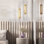 Lampa wisząca Sonata LED, 1-punktowa, wykonana z mosiądzu, o cylindrycznym kształcie, zawieszona nad stolikiem nocnym. W tle widoczna dekoracyjna ściana z pionowymi panelami oraz wazon z kwiatami. Wnętrze w jasnych odcieniach.