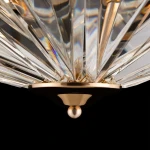Lampa sufitowa Facet 6-punktowa w kolorze złotym z dekoracyjnymi, przezroczystymi elementami. Ujęcie z dołu, pokazujące szczegóły kryształowych kloszy i złotą podstawę z kulistym wykończeniem. Tło czarne, podkreślające elegancję lampy.