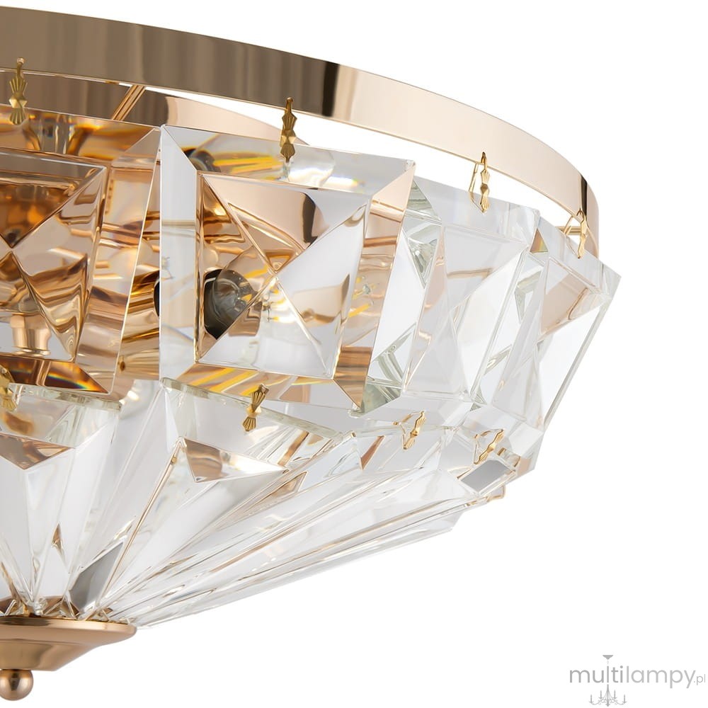 Lampa sufitowa Facet 6-punktowa w kolorze złotym, z kryształowymi zdobieniami w kształcie piramid. Widok z góry, ukazujący elegancki design oraz detale mocowania. Szklane elementy odbijają światło, tworząc efektowne refleksy.
