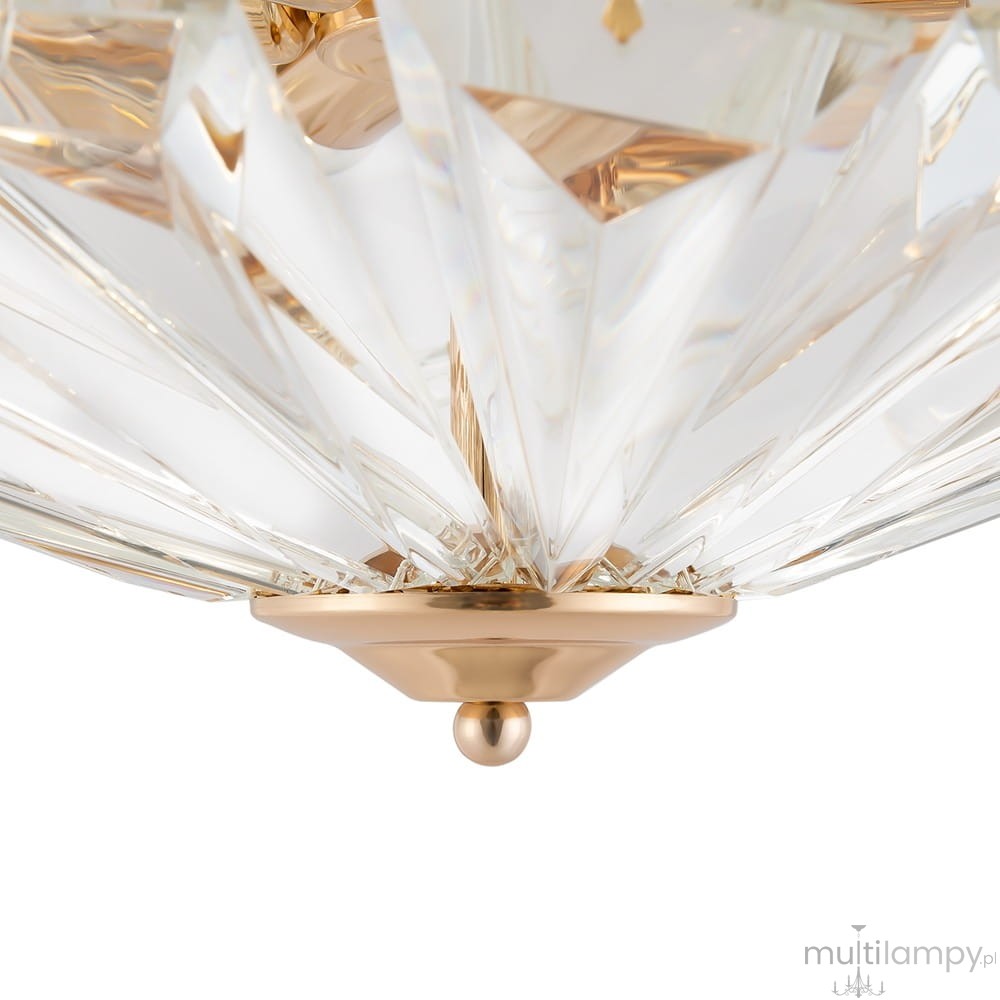 Lampa sufitowa 6-punktowa MOD094CL-06G z przezroczystym, szklanym kloszem o ostrych kształtach i złotą podstawą. Widoczny detal w postaci kulistego mocowania na dole. Produkt ukazany z bliska, na jasnym tle.