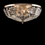 Sufitowa lampa Facet z sześcioma punktami świetlnymi, w złotej oprawie, z kryształowymi detalami w kształcie rombów. Lampa ma okrągłą podstawę i jest zamontowana na suficie, tworząc efektowne rozpraszanie światła.