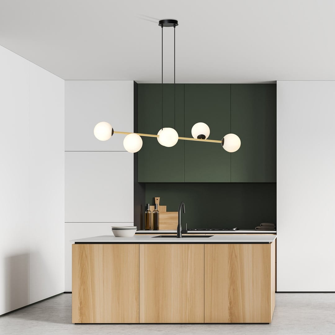 Lampa wisząca Gravity 6-punktowa w kolorze czarnym i złotym, z opalowymi kloszami. Ujęcie z góry, zawieszona nad kuchennym blatem. Tło stanowi nowoczesna zabudowa w odcieniach zieleni i bieli.
