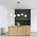 Lampa wisząca Gravity 6-punktowa w kolorze czarnym i złotym, z opalowymi kloszami. Ujęcie z góry, zawieszona nad kuchennym blatem. Tło stanowi nowoczesna zabudowa w odcieniach zieleni i bieli.