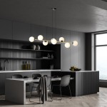 Lampa wisząca Gravity 8-punktowa w kolorze czarnym i złotym z opalowymi kloszami. Zawieszona na cienkich linkach, z okrągłymi kloszami rozmieszczonymi na prostokątnej ramie. Umieszczona nad stołem w nowoczesnej kuchni, w minimalistycznym otoczeniu.