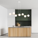 Lampa wisząca Gravity 8-punktowa w białym i złotym kolorze z opalowymi kloszami, zawieszona w kuchni nad drewnianą wyspą. Klosze mają okrągły kształt, a lampa jest zamontowana na białym suficie w nowoczesnym wnętrzu.