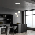 Lampa wisząca Royal 3-punktowa w kolorze białym i złotym, składająca się z trzech okrągłych kloszy, zawieszona na cienkich kablach. Produkt umieszczony w nowoczesnej kuchni z ciemnymi meblami i dużymi oknami.