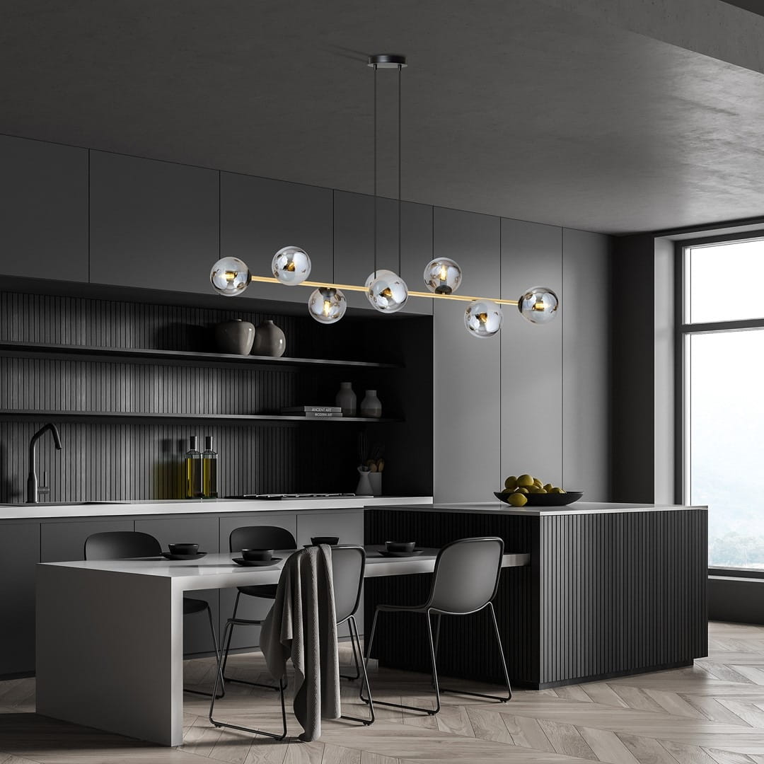 Lampa wisząca Gravity 8-punktowa w kolorze czarnym, złotym i grafitowym z kulistymi kloszami na złotej belce. Zawieszona nad nowoczesnym stołem w kuchni, otoczona ciemnymi meblami i jasnym tłem.