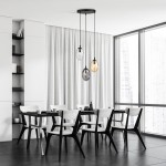 Lampa wisząca Astral 3-punktowa w kolorze czarnym z przezroczystymi kloszami w odcieniach multikolorowych. Produkt zawieszony na trzech linkach, umieszczony nad czarnym stołem w nowoczesnej jadalni z białymi krzesłami.