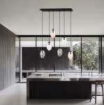 Lampa wisząca Astral 6-punktowa w kolorze czarnym z wielokolorowymi kloszami, zawieszona na długich linkach. Widoczna w nowoczesnej kuchni z dużymi oknami, z metalowym blatem i drewnianymi elementami.