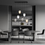 Lampa wisząca Astral 6-punktowa w kolorze czarnym z multikolorowymi kloszami, zawieszona na prostokątnej podstawie. Klosze mają różne kształty i kolory, w tym przezroczyste i matowe. Produkt umieszczony nad okrągłym stołem w nowoczesnym wnętrzu.