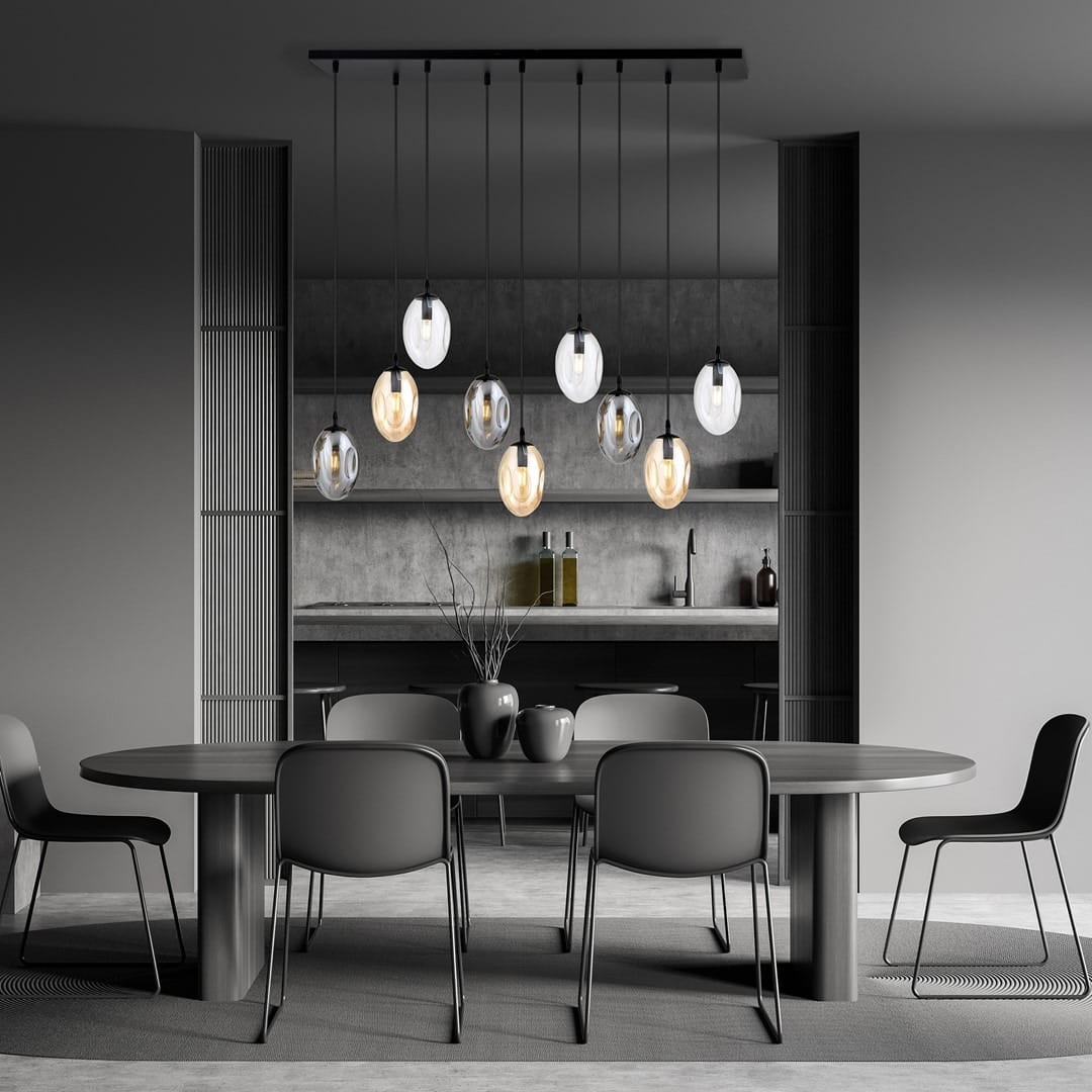 Lampa wisząca Astral 9-punktowa w kolorze czarnym i multikolorowym z szklanymi kloszami o owalnym kształcie, zawieszona na cienkich linkach. Ujęcie frontalne, w nowoczesnym wnętrzu z okrągłym stołem i krzesłami w odcieniach szarości.