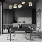 Lampa sufitowa Monza 4-punktowa w kolorze białym, złotym i grafitowym. Ułożona równolegle, z czterema przezroczystymi kloszami. Zawieszona nad czarnym stołem w nowoczesnej kuchni z szarym tłem i czarnymi krzesłami.