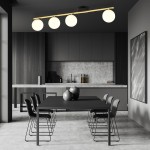 Czarna lampa sufitowa Monza 4-punktowa z metalowym stelażem w kolorze złotym, z trzema opalowymi kloszami, zamontowana równolegle nad czarnym stołem w nowoczesnej kuchni, w otoczeniu minimalistycznych krzeseł.