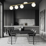 Lampa sufitowa Monza 4-punktowa w kolorze białym i złotym, z opalowymi kloszami, zamontowana na długiej, złotej listwie. Widok z góry, w nowoczesnej kuchni z czarnym stołem i siedzeniami. Tło w odcieniach szarości i drewna.