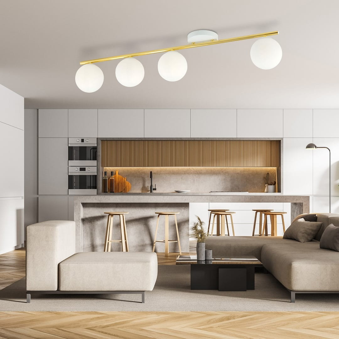 Lampa sufitowa Monza 4-punktowa w kolorze białym i złotym z opalowymi kloszami. Zawieszona na złotej listwie, składająca się z czterech okrągłych kul, oświetlająca nowoczesne wnętrze kuchni z jasnymi meblami i drewnianymi akcentami.