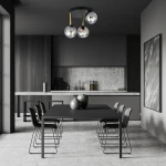 Lampa sufitowa Dolce 3-punktowa w kolorze czarnym, złotym i grafitowym, z trzema szklanymi kloszami. Zawieszona pod sufitem w nowoczesnej kuchni, nad czarnym stołem z dekoracyjnymi naczyniami. Kąt ujęcia frontalny, z widokiem na otoczenie.