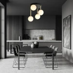 Czarna lampa sufitowa Dolce 4-punktowa z opalowymi kloszami, zawieszona na złotych linkach, umieszczona w nowoczesnej kuchni z ciemnymi meblami i betonowym blatem. Jasne, zaokrąglone klosze emitują miękkie światło.