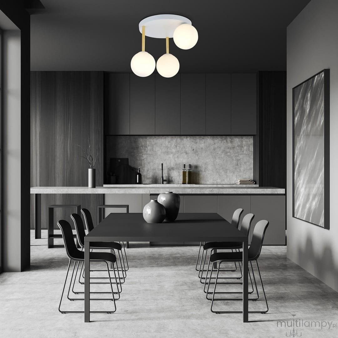 Lampa sufitowa Dolce 3-punktowa w kolorze białym i złotym z opalowymi kulami. Zawieszona na trzech złotych prętach, umieszczona w nowoczesnej kuchni z ciemnymi meblami i dużym stołem.
