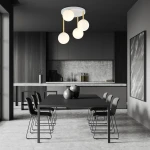 Lampa sufitowa Dolce 4-punktowa w białym kolorze z złotymi detalami, zawieszona na trzech cienkich linkach, z opalowymi, okrągłymi kloszami. Widok z dołu, umieszczona w nowoczesnej kuchni z czarnym stołem i krzesłami.