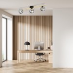 Lampa sufitowa Splendi 3-punktowa w kolorze czarnym, złotym i grafitowym z trzema szklanymi kloszami. Zawieszona poziomo, w nowoczesnym wnętrzu biura z drewnianą podłogą i ścianą w pionowe deski.
