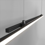 Czarna lampa wisząca LED Halo z dwoma punktami świetlnymi, o prostokątnym kształcie. Zawieszona na cienkich linkach, z matowym wykończeniem. Główna część lampy z białym źródłem światła, umieszczona w aluminiowej oprawie. Tło w jasnoszarym kolorze.