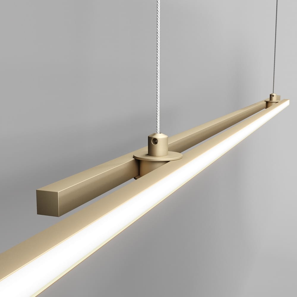 Lampa wisząca Halo LED 2-punktowa w kolorze mosiężnym. Posiada prostokątny kształt z białym panelem świetlnym na dolnej krawędzi. Zawieszona na cienkich linkach, montowana do sufitu, z widocznymi elementami mocującymi. Tło szare.
