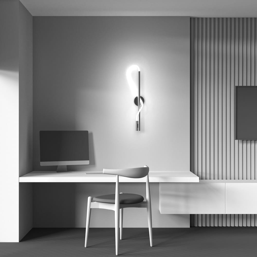 Złoty kinkiet LED Tau 1-punktowy MOD166WL-L12G3K zamontowany na ścianie, z eleganckim, prostym kształtem i delikatnym światłem. Widoczny w aranżacji biurowej, obok białego biurka i komputera. Tło w odcieniach szarości z teksturą.