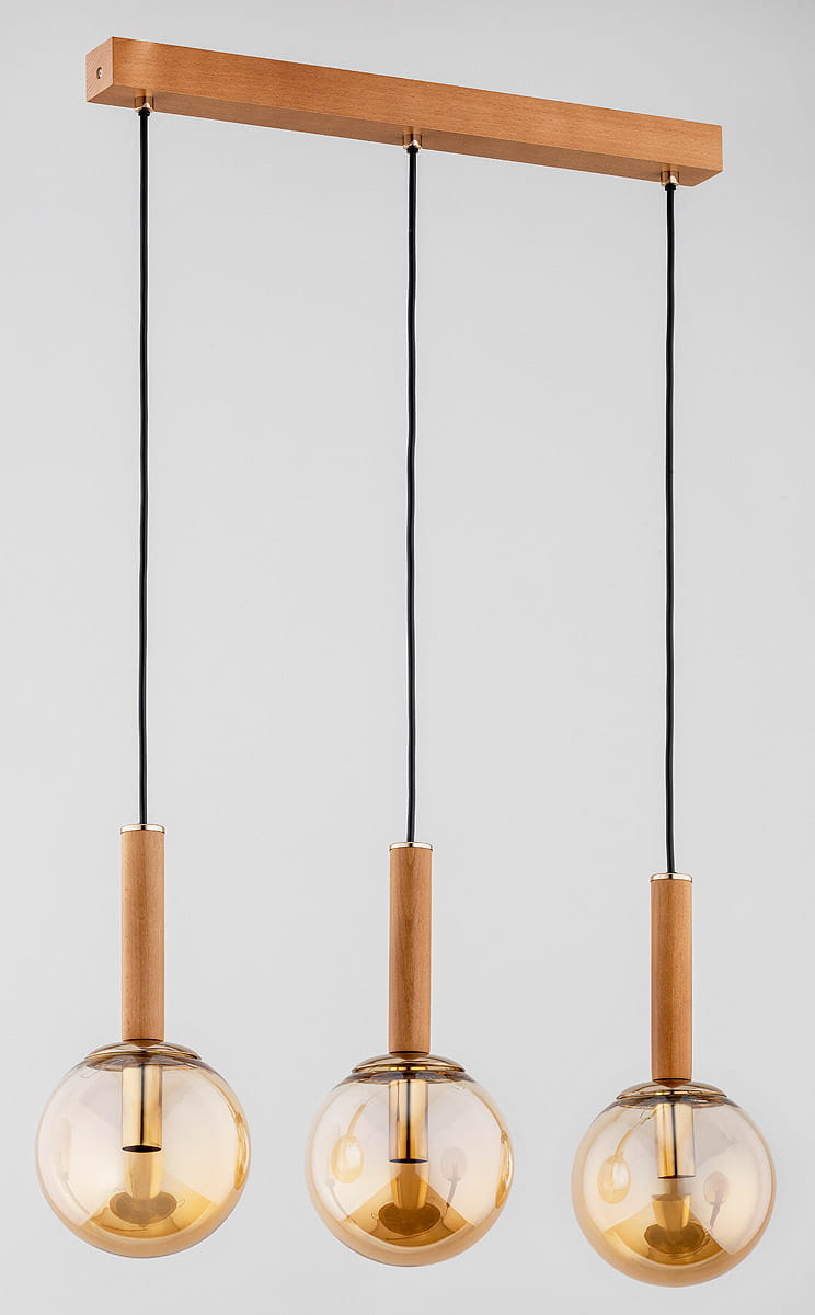 Lampa wisząca Tori 3-punktowa z drewnianą podstawą w kolorze złotym. Trzy przezroczyste kuliste klosze osadzone na drewnianych uchwytach, zawieszone na czarnych kablach. Ujęcie frontalne, na jasnym tle.