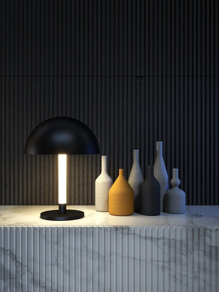 Czarna lampa stołowa Ray LED 1-punktowa z okrągłym kloszem, emitująca światło z centralnej, prostokątnej oprawy. Ustawiona na marmurowym blacie obok grupy ceramicznych wazonów w różnych kolorach i kształtach, na tle strukturalnej, ciemnej ściany.