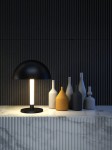 Czarna lampa stołowa Ray LED 1-punktowa z okrągłym kloszem, emitująca światło z centralnej, prostokątnej oprawy. Ustawiona na marmurowym blacie obok grupy ceramicznych wazonów w różnych kolorach i kształtach, na tle strukturalnej, ciemnej ściany.
