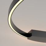 Czarny kinkiet Rim D80 LED z jednym źródłem światła. Okrągły, metalowy korpus z delikatnym podświetleniem LED, umieszczony na prostokątnej podstawie. Widoczny kształt w formie łuku, z jasnym światłem emitowanym z wewnętrznej krawędzi.