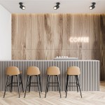 Czarna lampa sufitowa Tori SL3 w formie spotu, montowana na suficie, z jednym punktowym źródłem światła. Widoczna w nowoczesnej aranżacji wnętrza z drewnianą ścianą i barem, w otoczeniu jasnych hokerów.