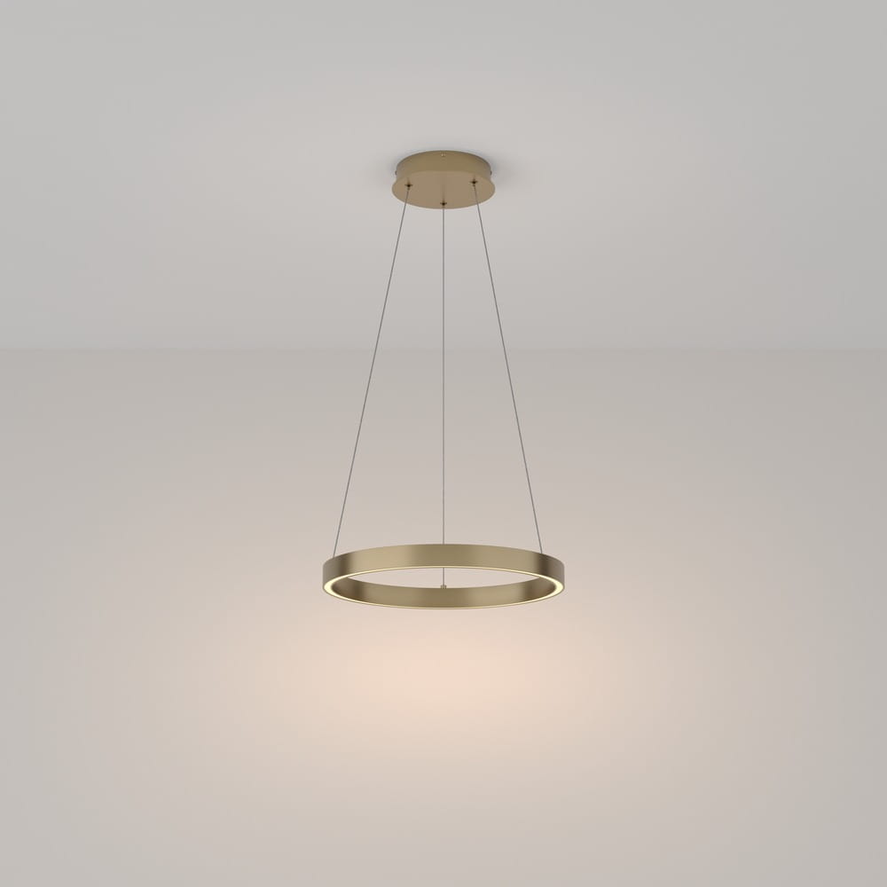 Lampa wisząca Rim D40 3000K w kolorze mosiądzu, w kształcie okręgu, zawieszona na cienkich linkach. Emituje ciepłe światło, umieszczona na jasnym tle. Idealna do nowoczesnych wnętrz.