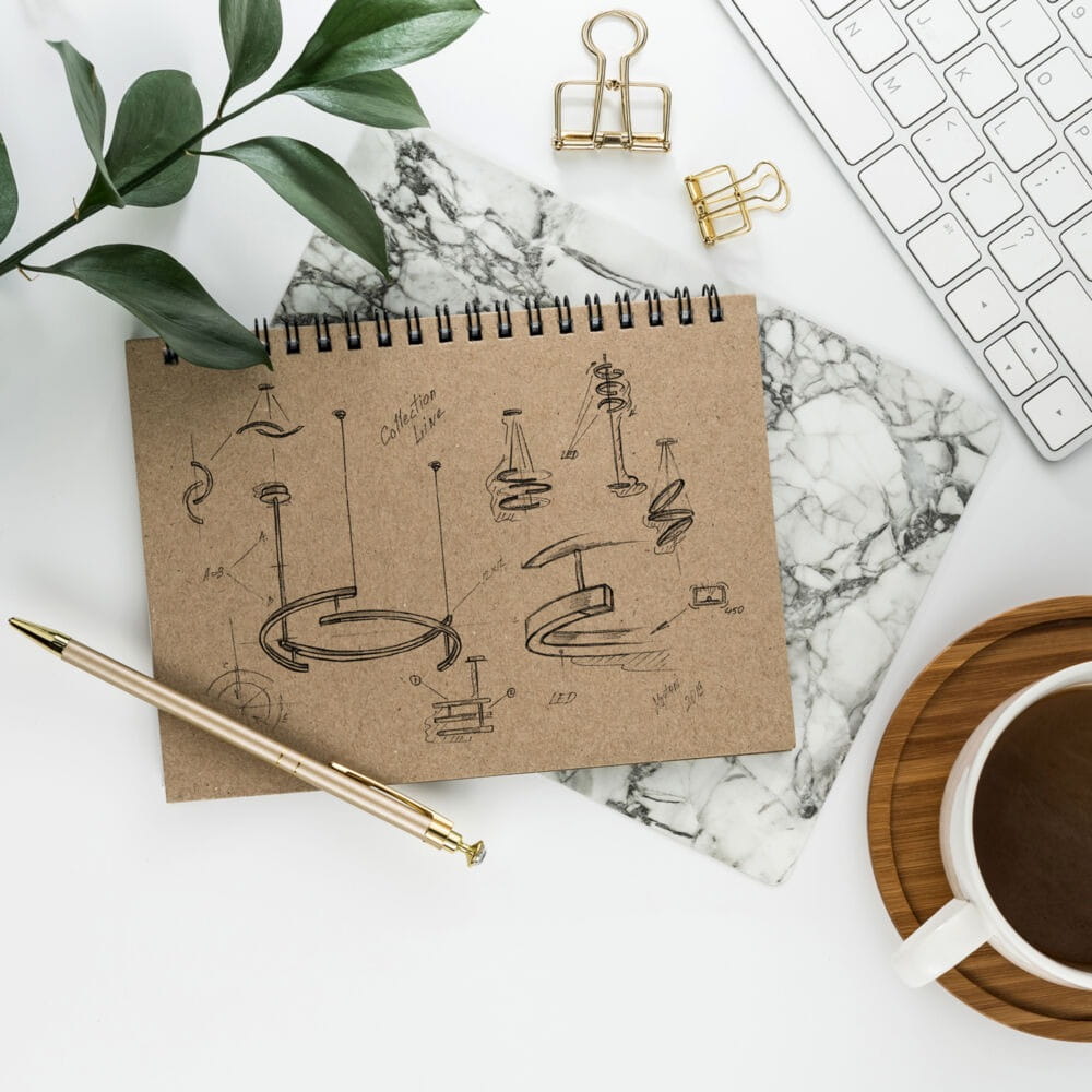 Czarne rysunki techniczne 3-punktowej lampy wiszącej LED Line 3000K na brązowym notatniku, z długopisem i filiżanką na tle marmurowej podkładki. Widać różne kształty i wymiary lampy.