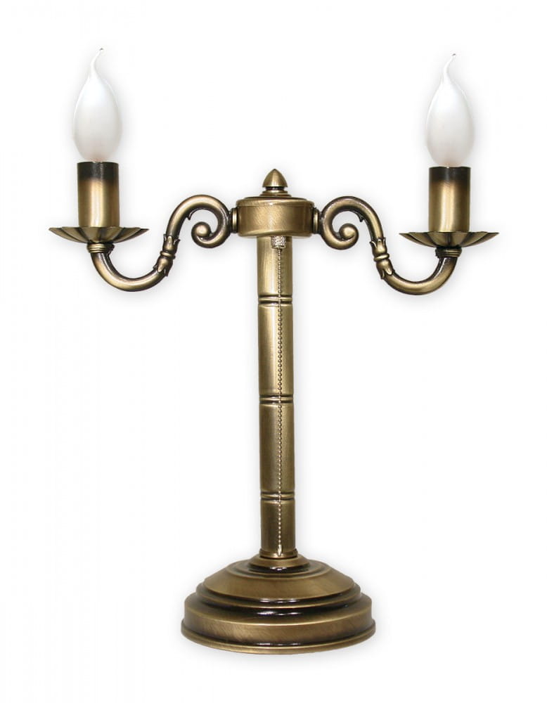 Lampka stołowa Prima O1008/L2 w kolorze antycznego mosiądzu. Posiada dwa źródła światła, z falistymi ramionami i eleganckimi kloszami w kształcie płomienia. Ustawiona na okrągłej podstawie, z widocznymi detalami w formie żłobień na nodze.