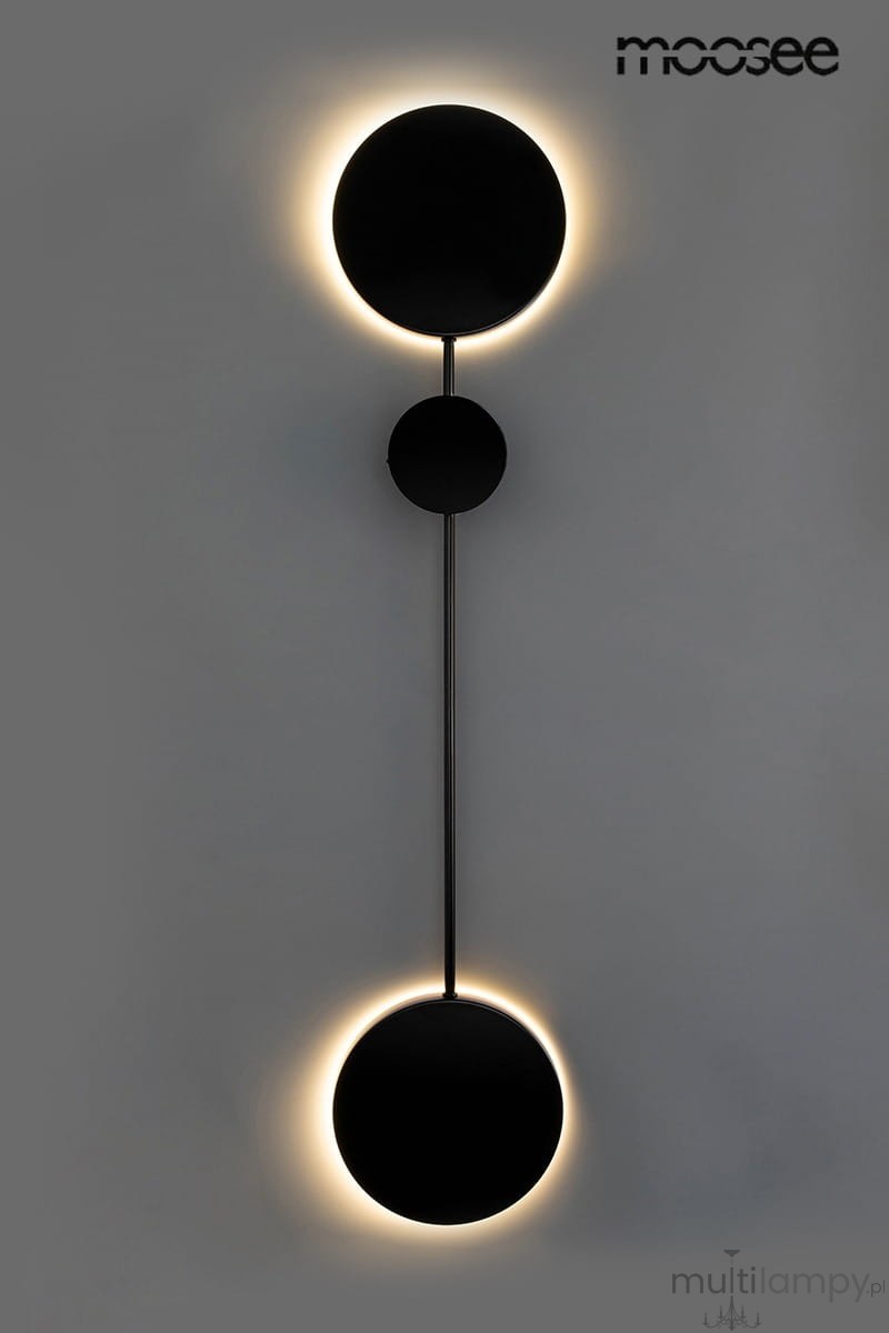 Kinkiet Shadow 2 LED w kolorze czarnym, składający się z dwóch okrągłych elementów o matowej powierzchni, zamontowany na cienkiej, prostokątnej podstawie. Oświetlenie emitowane jest wokół okręgów, tworząc efekt halo. Produkt umieszczony na jasnym tle.