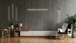 Czarny kinkiet 1-punktowy Ombre 80 LED, zamontowany na szarej, betonowej ścianie. Obok widoczna drewniana komoda z lampką oraz roślina. Kinkiet ma prostą, minimalistyczną formę, emitującą ciepłe światło.