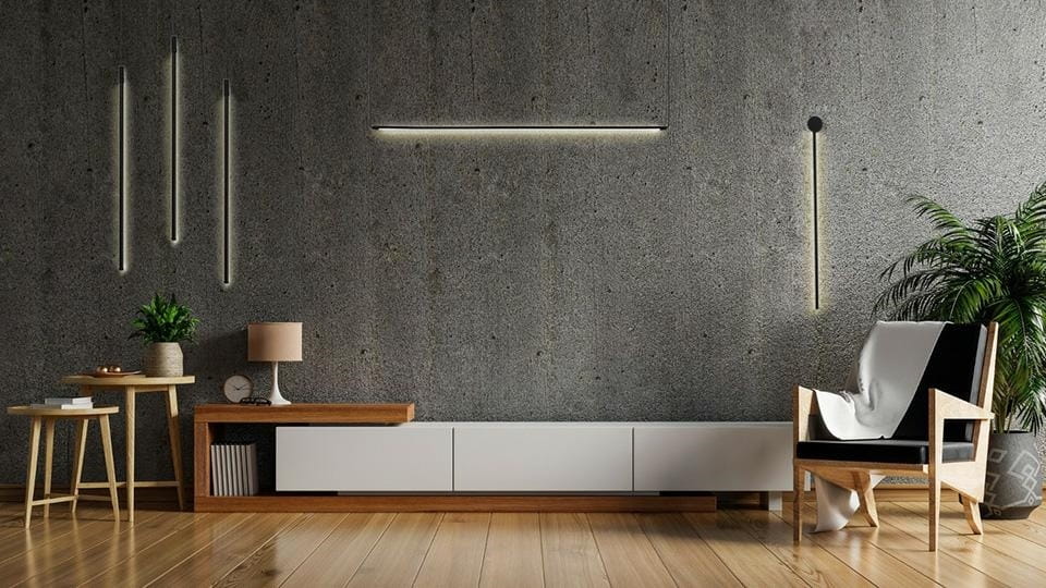 Czarny kinkiet Ombre 60 LED, 1-punktowy, zamontowany na ścianie w nowoczesnym wnętrzu. Oświetlenie w minimalistycznym stylu, obok drewniane meble, roślina i lampa stołowa. Tło z betonową fakturą.
