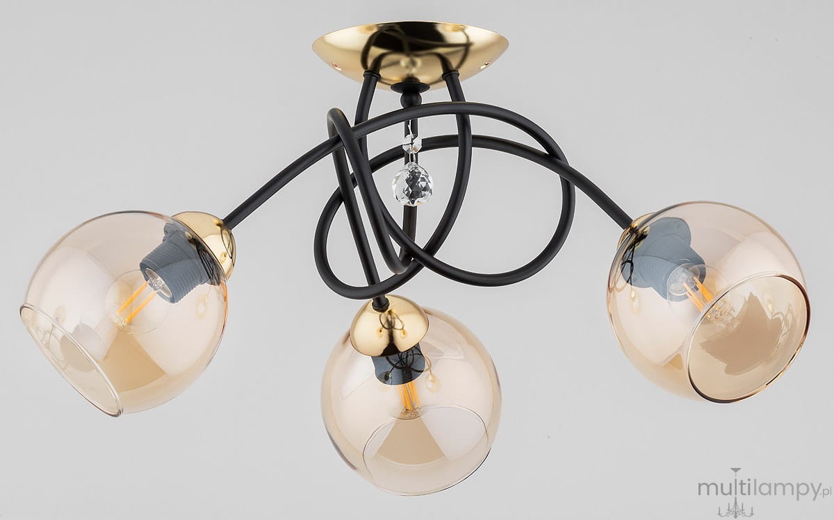 Modena Black lampa sufitowa 3-punktowa w kolorze czarnym i złotym, z trzema przezroczystymi kloszami w kształcie kul. Lampa ma czarne przewody i złoty uchwyt sufitowy, z dekoracyjnym kryształkiem na środku.