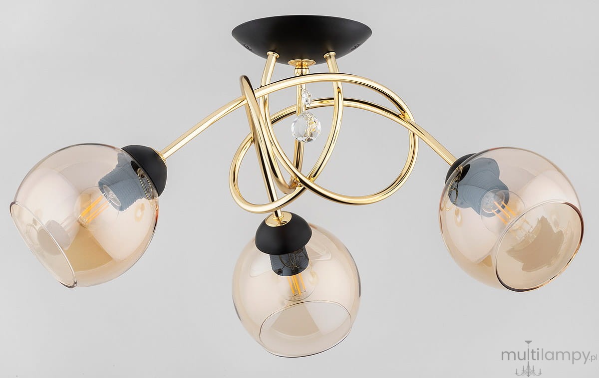 Lampa sufitowa Modena Black, 3-punktowa, w kolorze złotym i czarnym. Konstrukcja z eleganckimi, przezroczystymi kloszami w kształcie kul, umieszczonymi na zakrzywionych ramionach. Centralny element z ozdobnym kryształem.