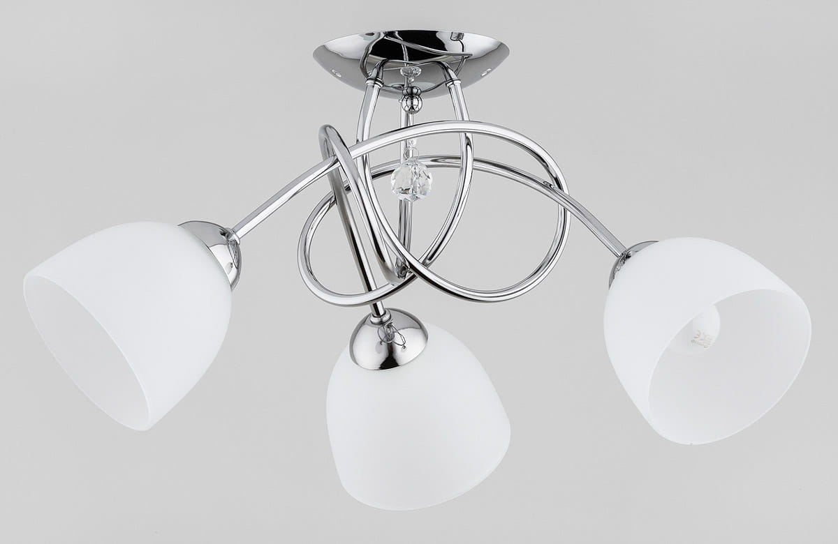 Lampa sufitowa Modena Silver 3-punktowa w chromowanej oprawie. Posiada trzy białe klosze w kształcie stożka, które są umieszczone na elastycznych ramionach, tworząc nowoczesny design. Elementy dekoracyjne to chromowane detale oraz kryształowy akcent.