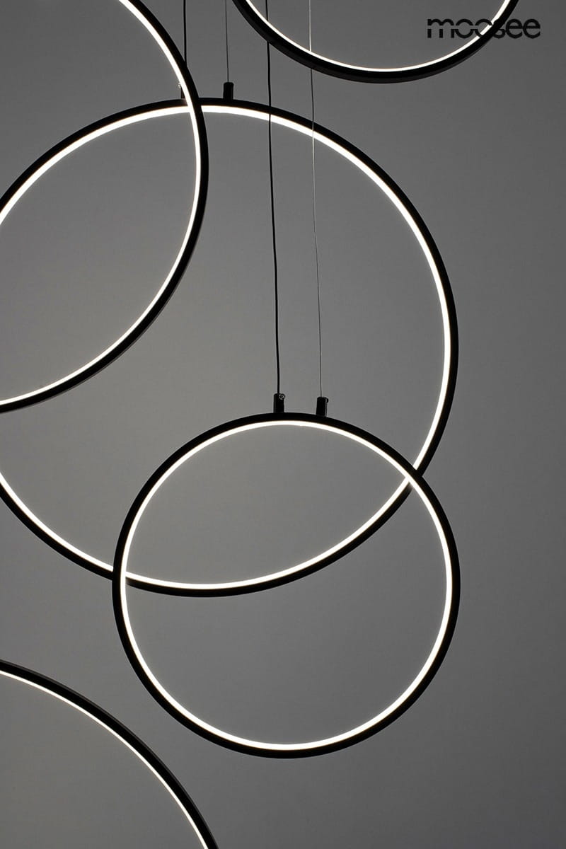 Czarna lampa wisząca Circulo Six LED z sześcioma okręgami, podwieszona na cienkich linkach. Okręgi oświetlone są jasnym światłem LED, tworząc nowoczesny efekt. Kąt ujęcia z góry, na szarym tle.