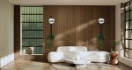 Kinkiet LED Plant Wall w kolorze czarnym, z okrągłą, białą oprawą, zamontowany na drewnianej ścianie. W tle widoczna jasna, nowoczesna sofa oraz rośliny, co tworzy przytulny klimat wnętrza.