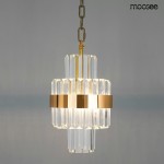 Złota lampa wisząca Impero LED z przezroczystymi, pionowymi elementami szklanymi. Ujęcie z przodu, zawieszona na łańcuchu. Światło wydobywa się z centralnej części, podkreślając elegancki design. Tło w stonowanej szarości.