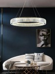 Złota lampa wisząca Liberty 40 LED, o okrągłym kształcie, zawieszona na cienkich linkach. Wykonana z przezroczystych materiałów, tworzy efektowne odbicia światła. Służy jako elegancka dekoracja wnętrza, umieszczona nad sofą w nowoczesnym salonie.