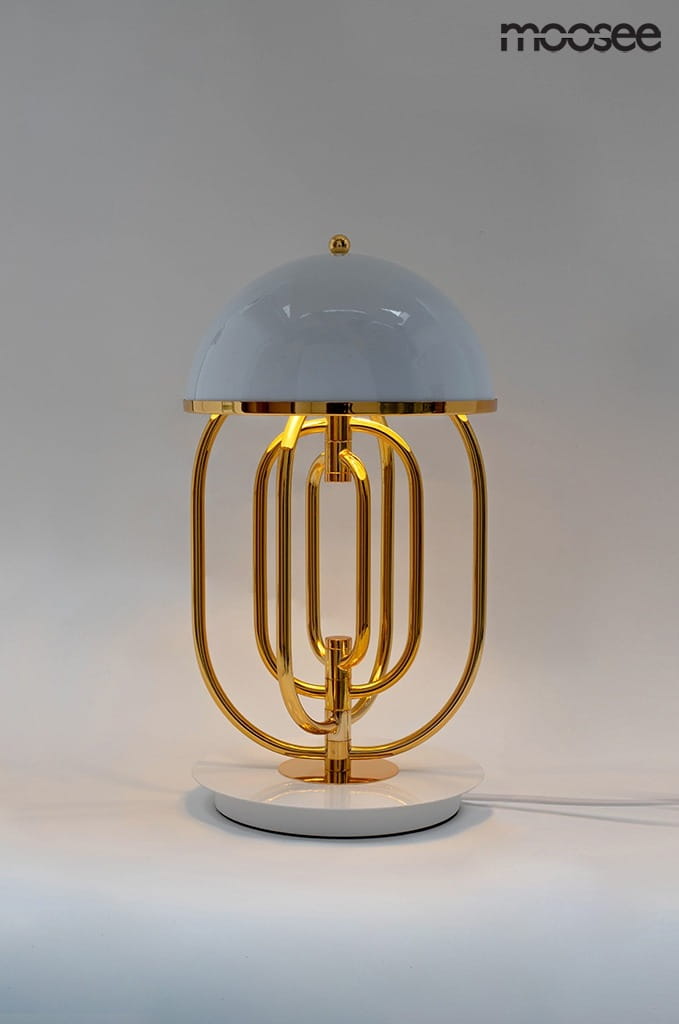 Lampa stołowa Bottega z dwoma punktami świetlnymi, z okrągłą białą kloszem i złotą metalową podstawą. Kształt lampy jest nowoczesny, z dekoracyjnymi metalowymi rurkami, umieszczona na okrągłej białej podstawie. Tło neutralne.